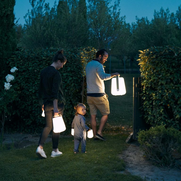A family walks with Fermob Balad Lamps at night