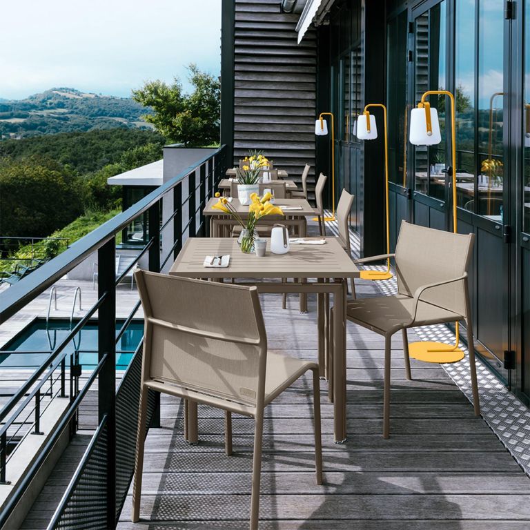 Fermob Cadiz chairs and Costa square table settings in Nutmeg on a narrow commercial terrace