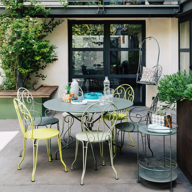 Fermob Montmartre metal French chairs and large round table sit in a modern courtyard