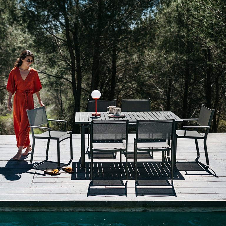 Woman walks around a Fermob Costa aluminium outdoor setting poolside