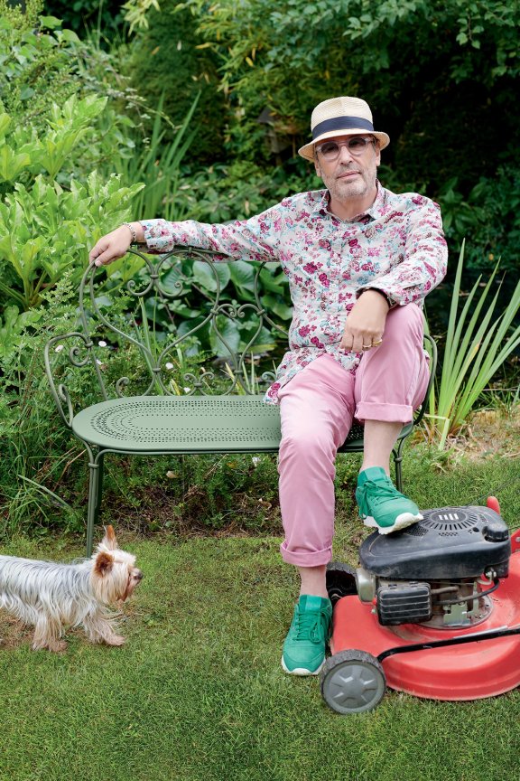 Man sitting on Fermob 1900 metal bench in Cactus colour in a garden