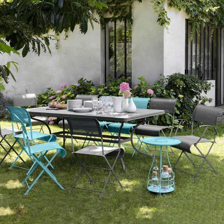 Fermob Romane extending table and a collection of Dune folding outdoor chairs sitting in a garden