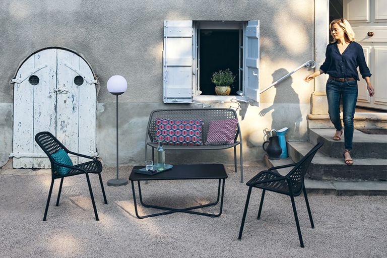Fermob Croisette casual armchairs, bench and coffee table with Mooon! outdoor lamp in a courtyard