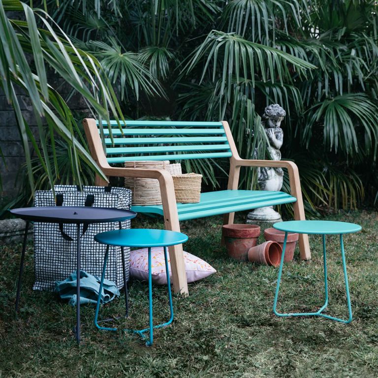 Fermob Somerset Garden Bench With Teak Ends and Metal Slats in Lagoon Blue. Sitting On Grass With Cocotte Side Tables